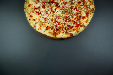 Smoked pizza. chicken, pomegranate berries and cheese. Wooden plate. Gray background. Restaurant