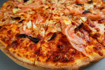 Pepperoni pizza. spicy salami, mozzarella, chilli, gherkins. Wooden plate. Gray background. Restaurant