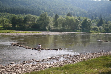 lonely man, river, forest, mountains in the Carpathians, Ukraine