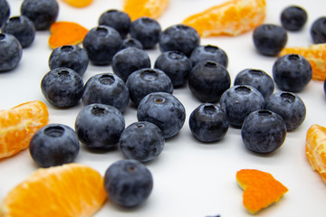 Fresh blueberry  with mandarin slices on white background. A composition of the blueberries and mandarin pieces which is organic and healthy. The berries and fruit full of vitamins.