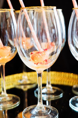 Empty wine glasses decorated with colorful ice and a pink straw