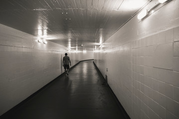 Long underground pedestrian tunnel which is empty with one person walking alone