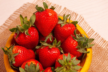 strawberries in bowl on jute cloth background