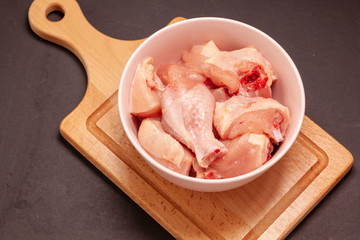 raw chicken in bowl on wooden cutting board background
