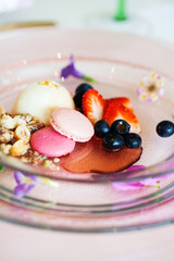 Beautifully arranged ice cream dessert with pink cookies, blueberries and strawberries