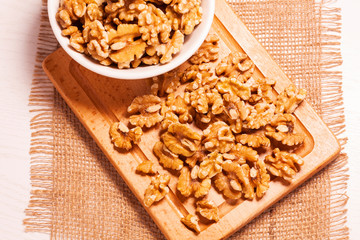 walnuts in bowl with jute cloth and wooden board background