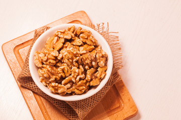 walnuts in bowl with jute cloth and wooden board background