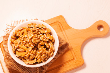 walnuts in bowl with jute cloth and wooden board background