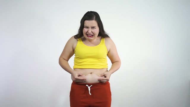 Overweight big size girl touches her belly and feels sad and unhappy 
