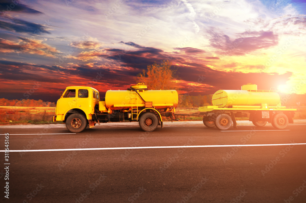 Canvas Prints old soviet fuel tanker truck shipping fuel on the countryside road with forest against sky with suns