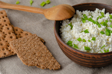 A glass bottle with kefir and kefir grains with bread rolls on the wooden table