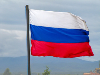 photo of the Russian flag in white-blue-red color against a cloudy summer sky                               