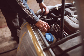 Close up image of man fixing car engine