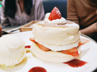 Homemade fluffy pancake and sweet syrup - Delicious pancakes with strawberry sauce and ice cream on dining table in the cafe restaurant