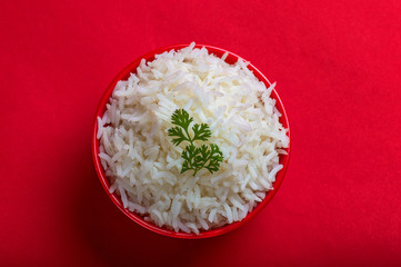 Cooked plain white basmati rice in a red bowl on red background