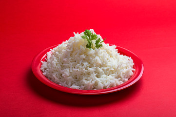 Cooked plain white basmati rice in a red plate on red background