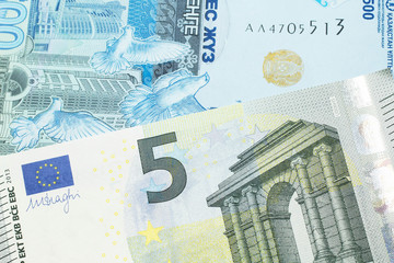 A five Euro note from the European Union eurozone paired with a blue, five hundred tenge bank note from Kazakhstan