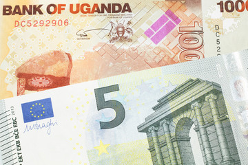 A five euro European bank note with a one thousand Ugandan shilling bill close up in macro