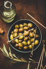Flat-lay of fresh harvested seasonal pickled green Mediterranean olives over dark rusty background,...