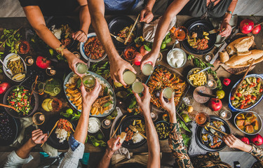 Flat-lay of family clinking glasses over table with Turkish cuisine lamb chops, quince, bean, vegetable salad, babaganush, rice pilav, pumpkin dessert and lemonade, top view. Middle East cuisine - obrazy, fototapety, plakaty