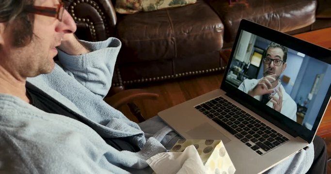 Sick man using a laptop computer for a telemedicine appointment with his doctor
