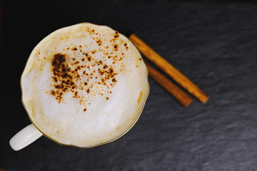 Cup of Italian coffee (cappuccino) with cinnamon on black board.