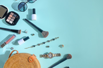 Blogging Beauty Concept. Professional female makeup accessories, watches, bracelet, sunglasses and a fashionable bag on a blue background. Female background and fashion. Creative light. Banner.