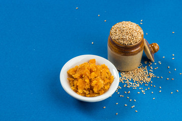 Sesame Seeds in clay pot with Jaggery in bowl on blue background