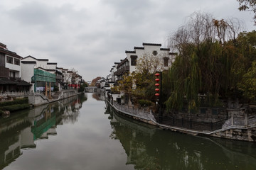 Fototapeta premium Qinhuai River viewed from Wenzheng Bridge in a cloudy winter morning with historical Taoye Ferry on right bank and traditional buildings on riversides, Nanjing, Jiangsu, China.
