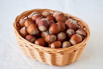 Obraz premium Hazelnuts in a basket on a light background