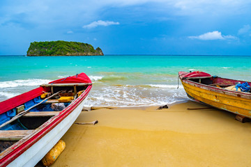 Colorful old wooden fishing boats docked by water on a beautiful beach coast land. White sand sea...