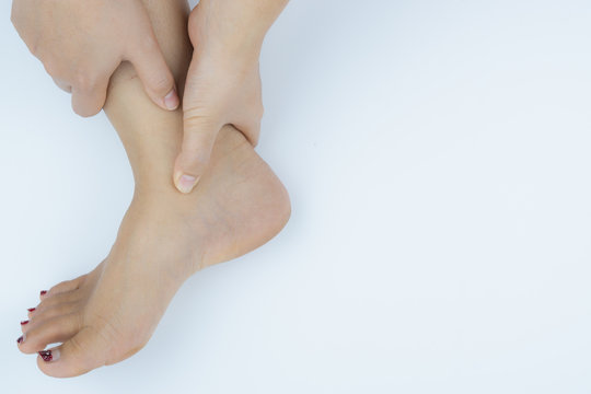 Closeup woman holds ankle pain on white background. Health care and medical concept.
