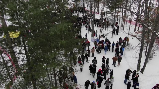 Winter party in the woods in Traverse City Michigan 4K drone shots over forest and open woods in winter snow covered scene people at event