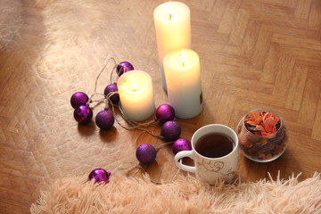 Obraz na płótnie Canvas burning candles next to purple garland balls.