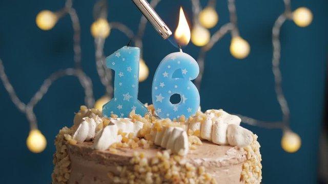 Birthday cake with 16 number candle on blue backgraund. Candles are set on fire. Slow motion and close-up view