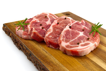 raw pork steak on wood cutting board. Pork with spices: rosemary and pepper. Close-up raw pork steaks.