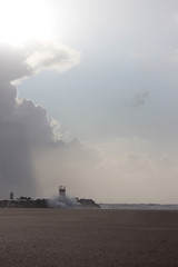 Fototapeta premium Lighthouse with cloudy sunny sky at the beach