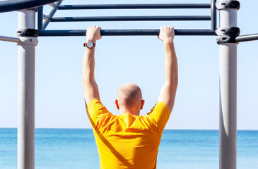 Guy on the horizontal bar on the beach sports ground