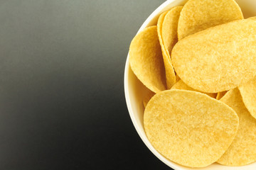 potato chips on bowl on black background.