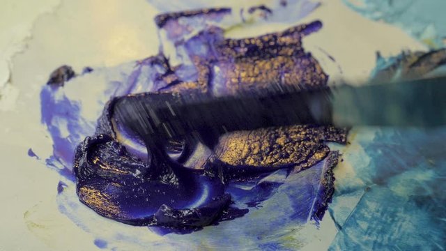 Close up of a palette knife blending phantom blue oil paint in slow motion