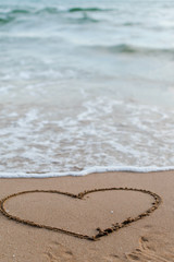 Hand drawn of heart picture on the sand with sea wave at Phuket beach Thailand.Concept for valentine 's day theme ,Holiday ,Postcard ,Romantic card ,Day off ,Wedding marriage love card.
