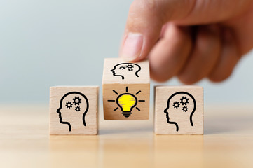 Concept creative idea and innovation. Hand flip over wooden cube block with head human symbol and light bulb icon