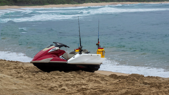 Red And White Fishing Jetski On The Beach With The Ocean In The Background