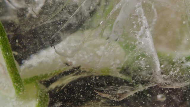 Filling glass of ice and slices of lime with sparkling water macro shot, making a mojito, bubbles in liquid, slow motion, shot on Red Weapon Helium 8k