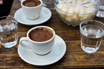 a cup of delicious aromatic invigorating espresso on a wooden table. A glass of refreshing water.