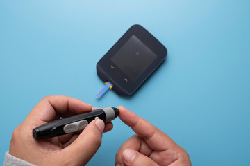 Using lancet pen for taking blood sample for sugar level check using glucose meter, diabetes concept