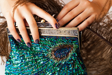 woman hands with shiny manicure holding little purse peacok feather, cosmetic and fashion people concept