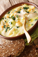 Creamy gnocchi soup with chicken, spinach and vegetables close-up in a bowl. vertical