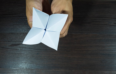 The man's hand is holding a paper that predicts the fate known as Paper Fortune Tellers. To predict the future, work, love, fate, sometimes used as a fun game to play. There is space for copy space.