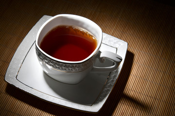 White cup of tea on a white saucer on bamboo napkin